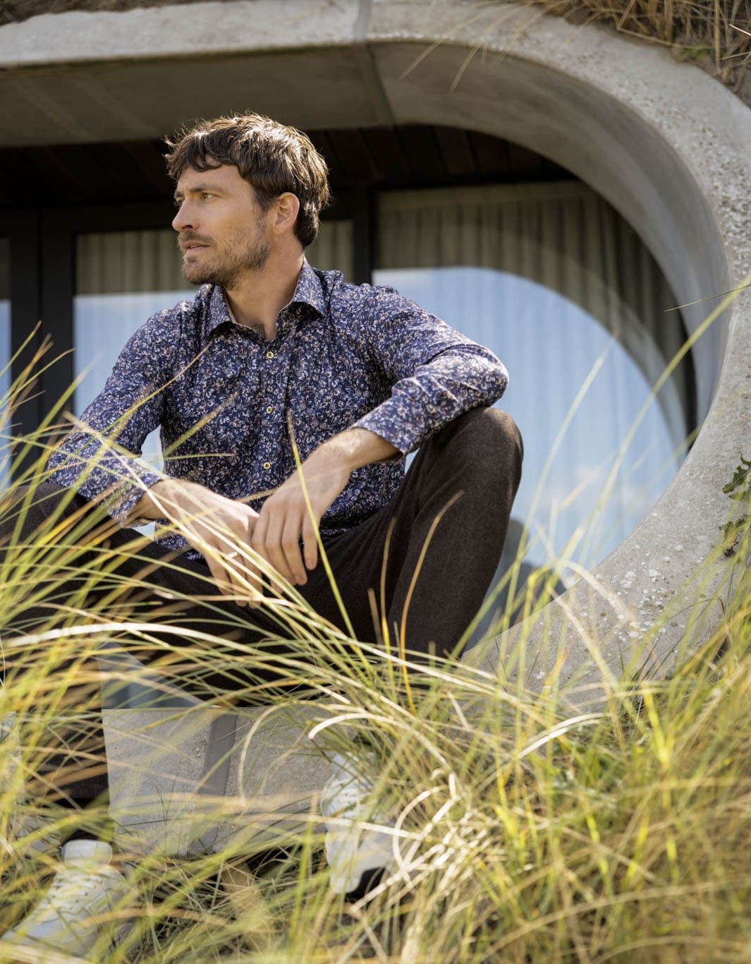 Man in een Giordano overhemd met bloemenprint in de duinen